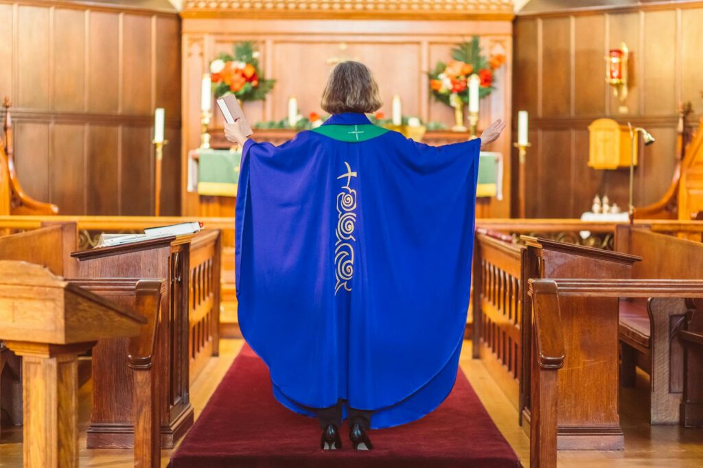 woman priest in blue chasuble standing in front of an altar