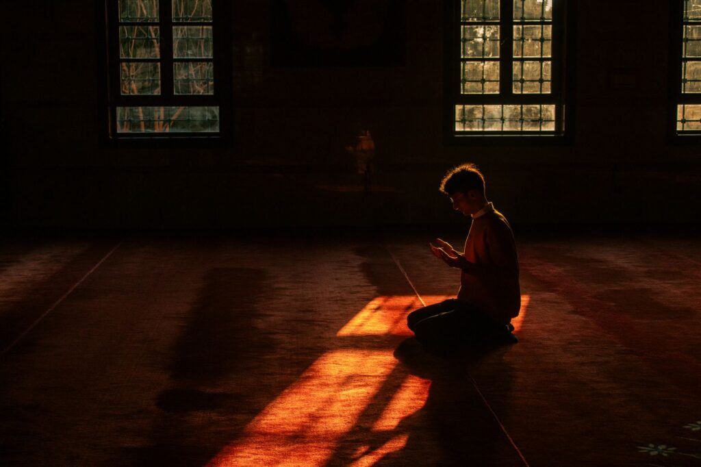 silhouette of a person praying in a mosque