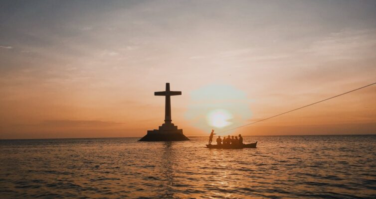 photo of cross in an ocean during dawn
