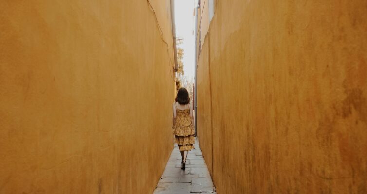 back view of a woman walking in a narrow alley