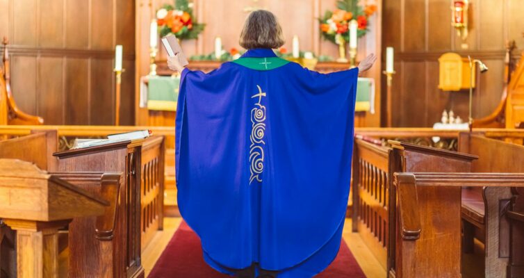 woman priest in blue chasuble standing in front of an altar