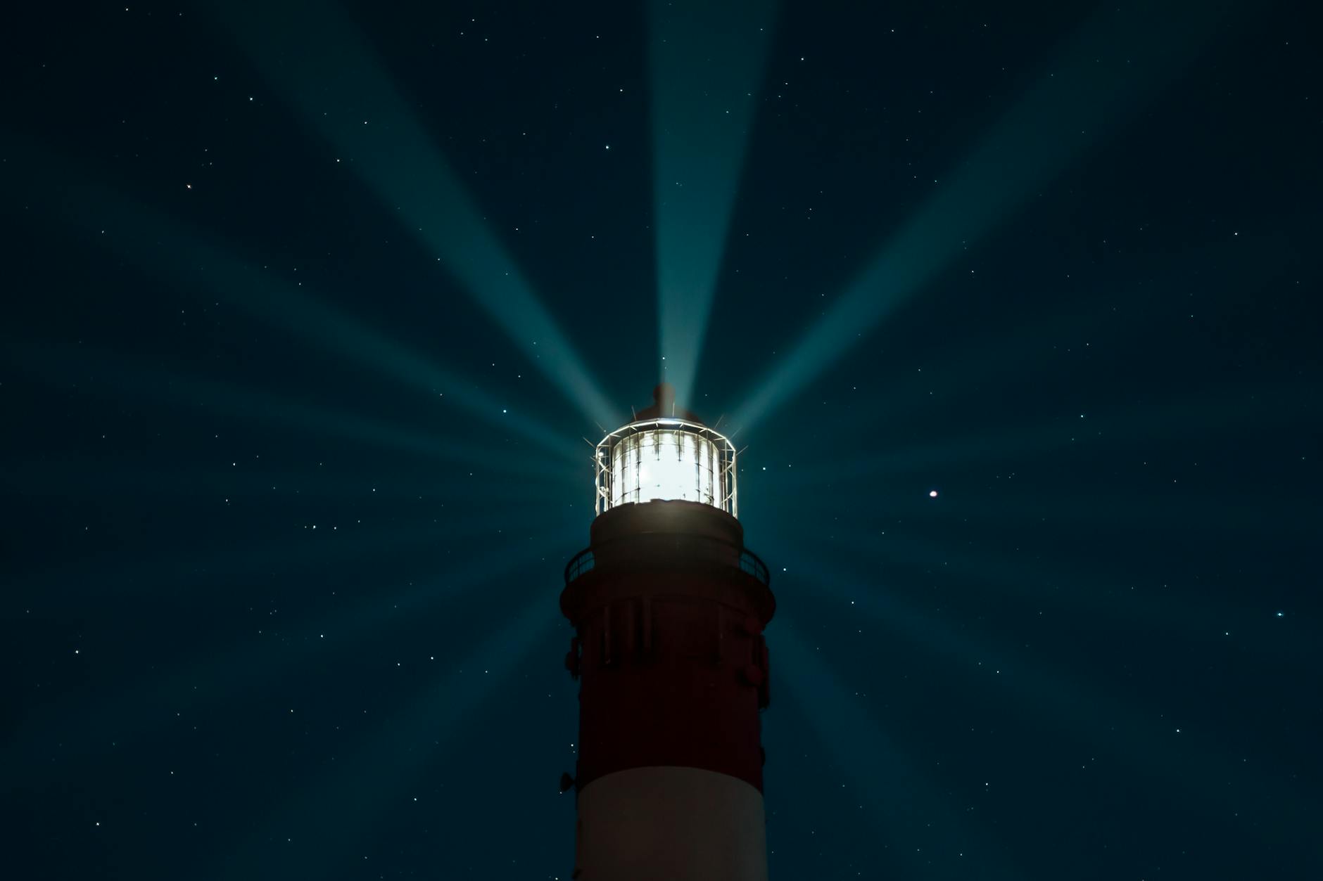 illuminated lighthouse under night sky
