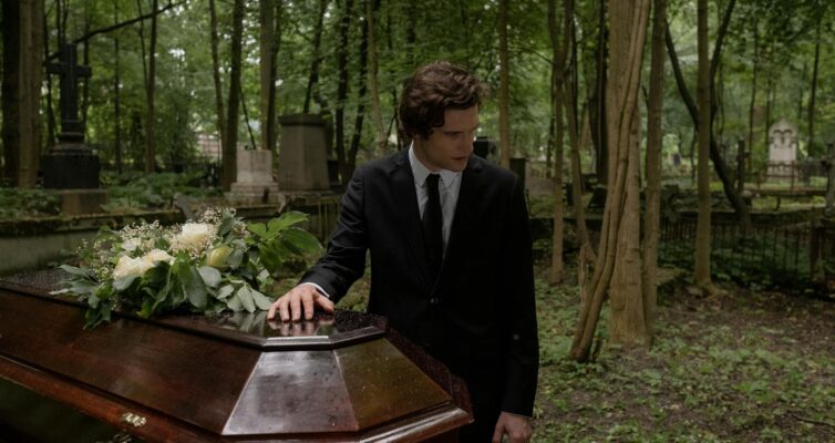 man in black suit standing near the coffin