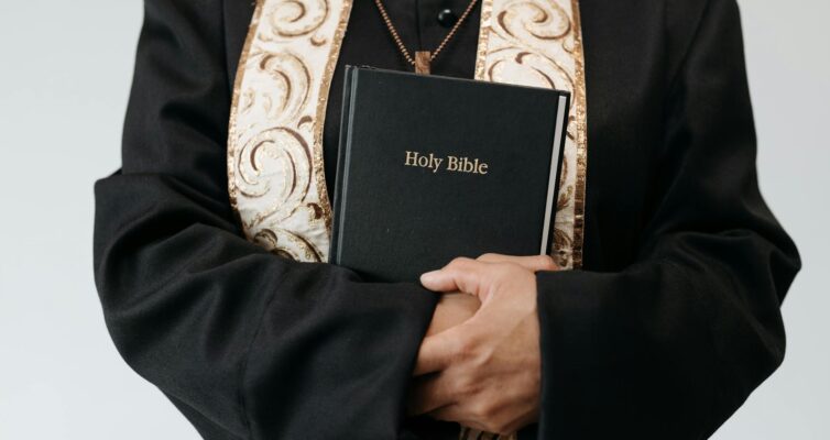 person wearing a cassock holding a bible