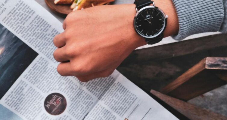 person wearing watch near the newspaper