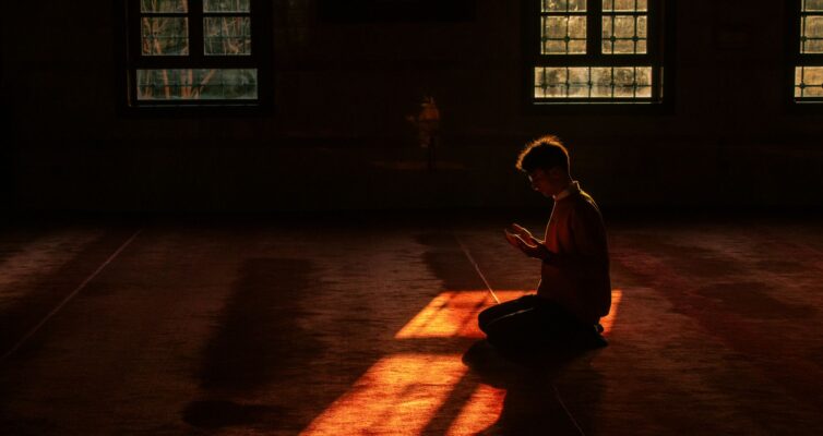silhouette of a person praying in a mosque