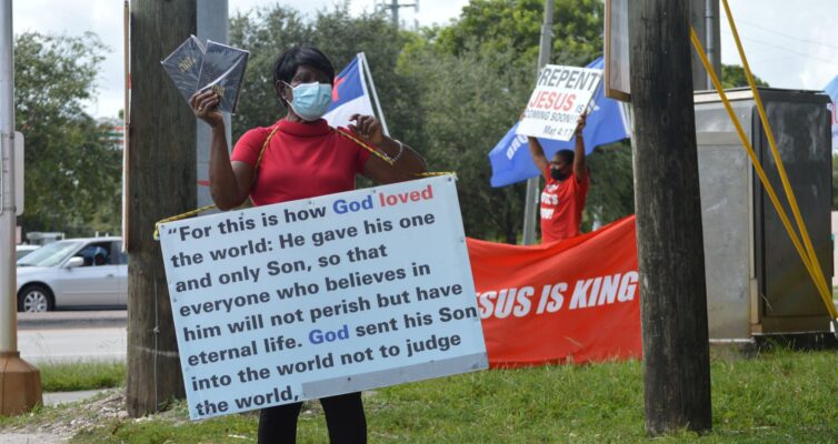 woman in medical mask and board with script on street