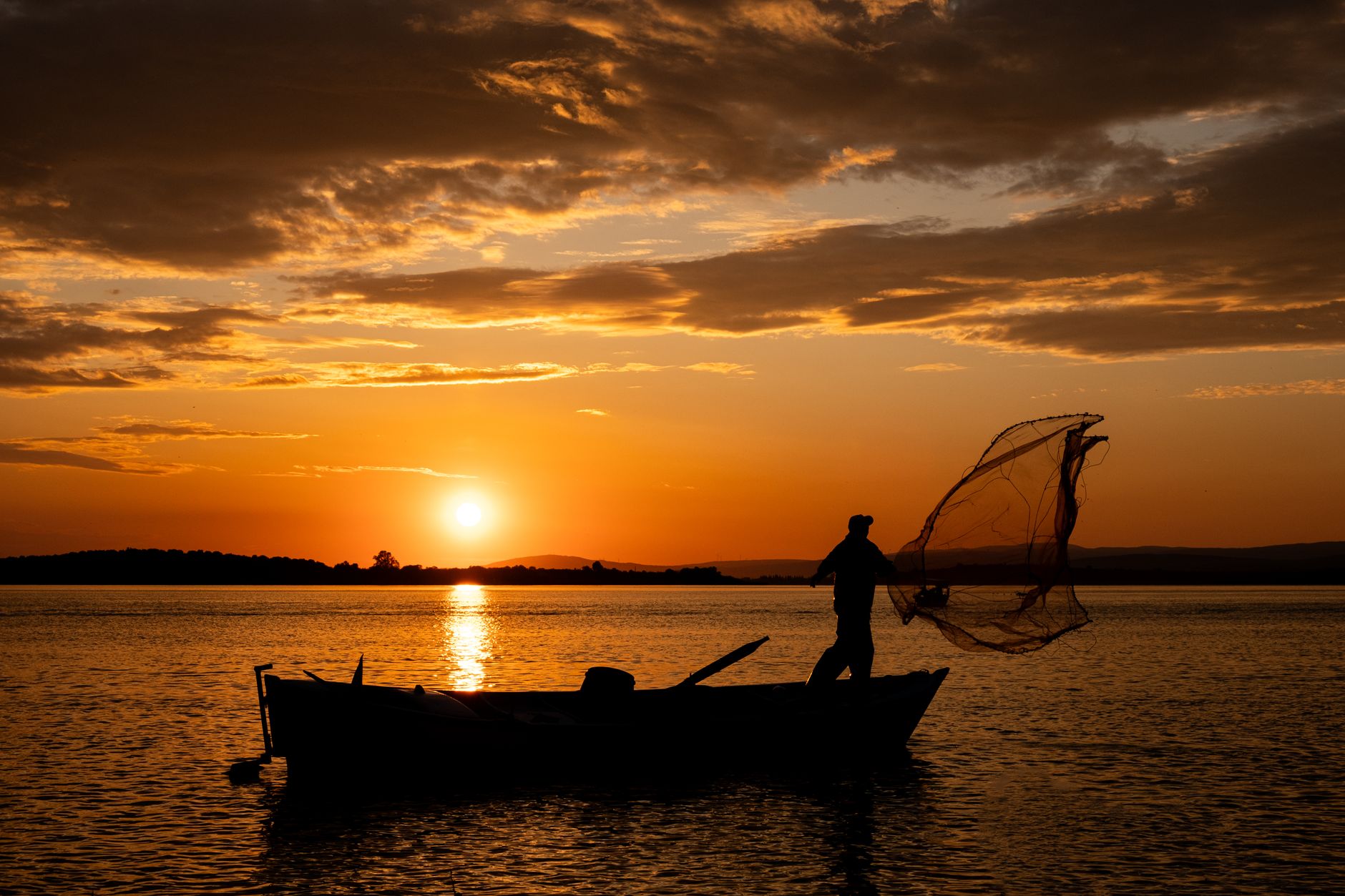 silhouette of fisherman casting net at sunset in bursa