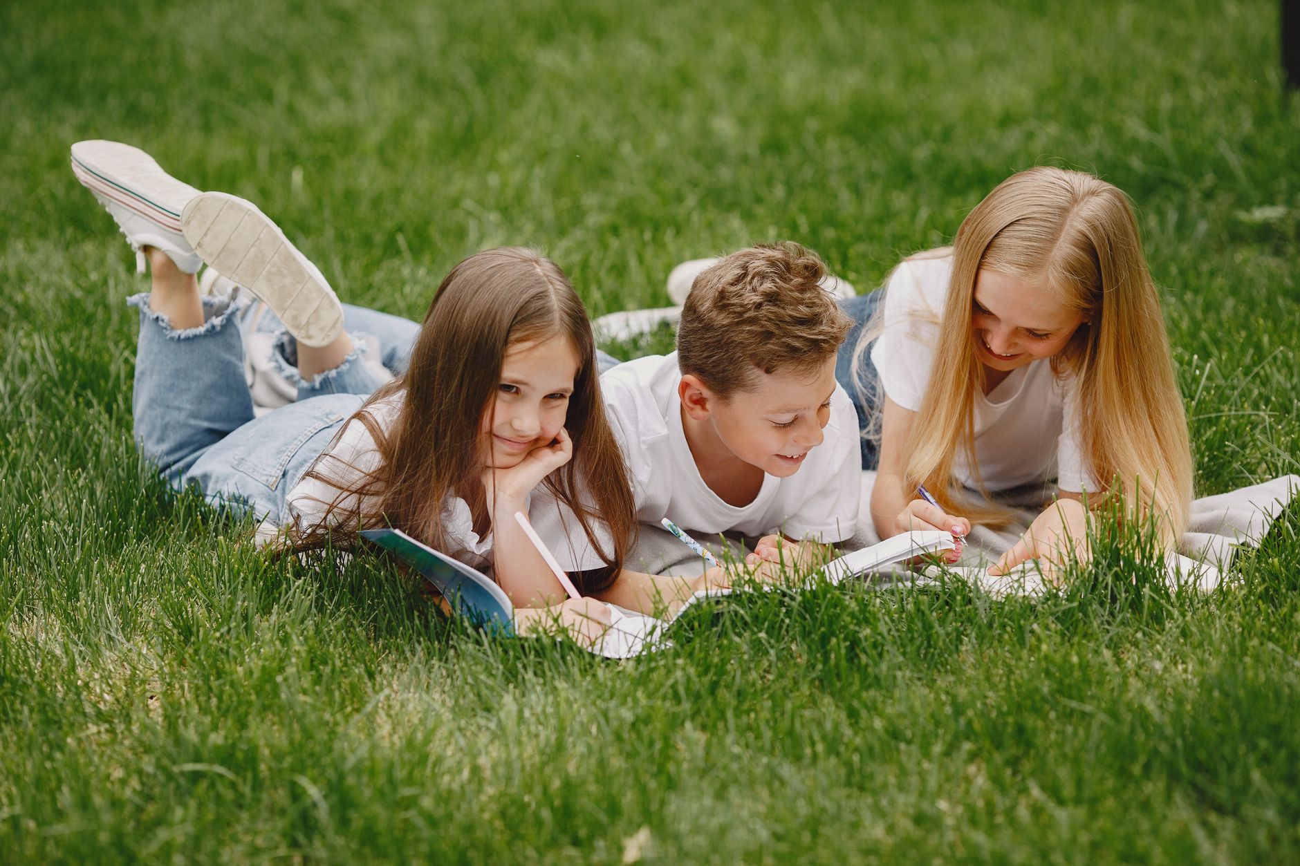 kids lying on lawn and doing homework